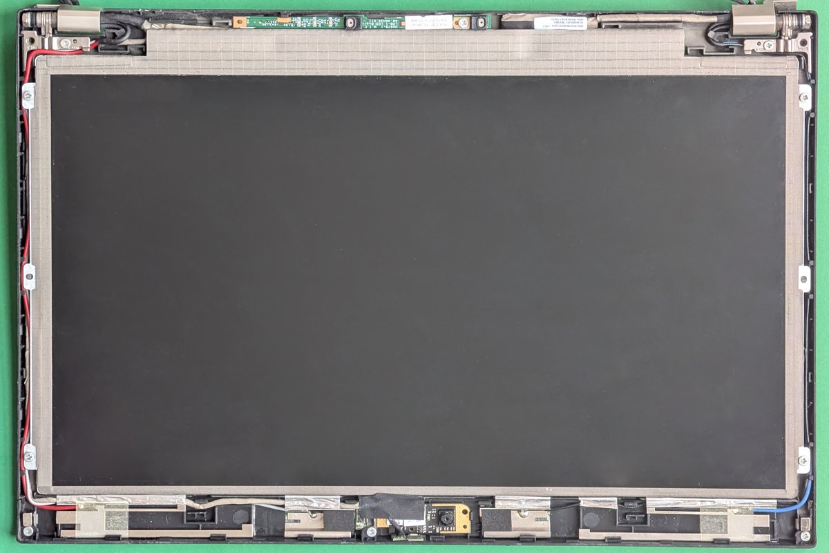 Desmontagem de tela de notebook Lenovo ThinkPad X220 mostrando painel LCD, cabos flat e dobradiças em bancada de reparo